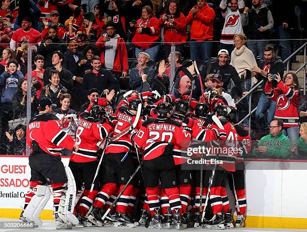 The New Jersey Devils team surrounds John Moore after he scored the game winner in overtime against the Dallas Stars on January 2,2016 at Prudential...