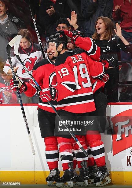 Travis Zajac and Kyle Palmieri congratulate John Moore of the New Jersey Devils after Moore scored the game winning goal in overtime against the...