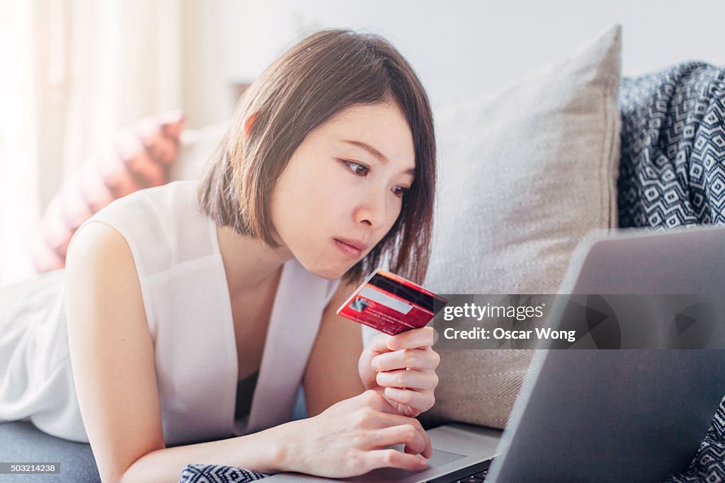 Young woman holding credit card and using laptop