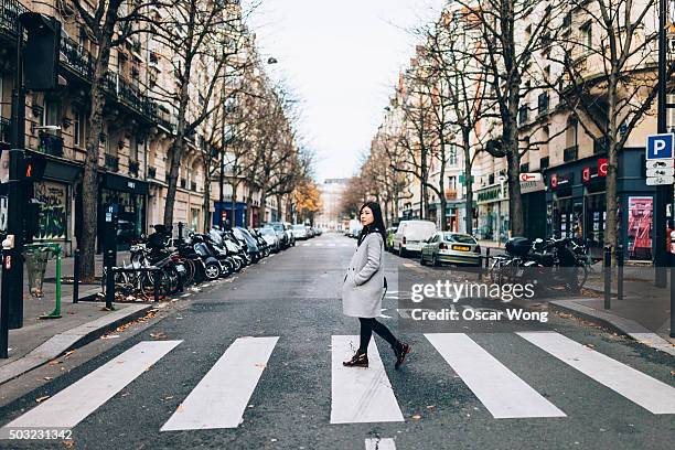 asian woman crossing zebra in paris - paris street woman stock pictures, royalty-free photos & images