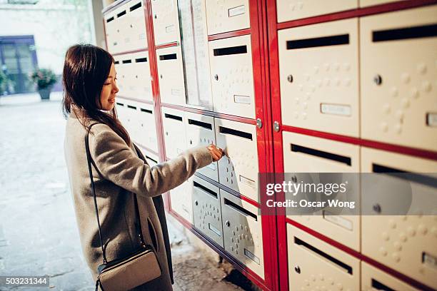 young lady checking mailbox - briefkasten stock-fotos und bilder
