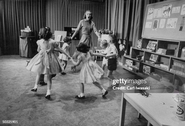 Hostess Susan Gifford of the TV show 'Romper Room' singing All Around the Mulberry Bush with the children.