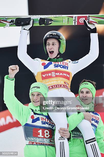 Peter Prevc of Slovenia celebrates with team mates Anze Lanisek and Tilen Bartol as he wins the Innsbruck 64th Four Hills Tournament ski jumping...