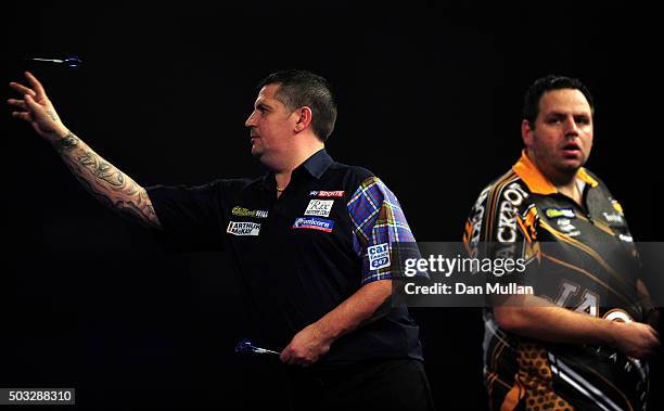 Gary Anderson of Scotland throws as Adrian Lewis of England looks on during the final match on Day Fifteen of the 2016 William Hill PDC World Darts...