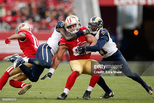 Vance McDonald of the San Francisco 49ers is tackled by Janoris Jenkins and Maurice Alexander of the St. Louis Rams during their NFL game at Levi's...