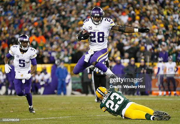 Adrian Peterson of the Minnesota Vikings hurdles Damarious Randall of the Green Bay Packers during the third quarter of their game at Lambeau Field...