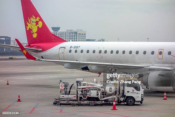 Ground service men are checking a passenger plane on tarmac. A passenger plane of Air China stops on tarmac. The year of 2015 is the most profitable...