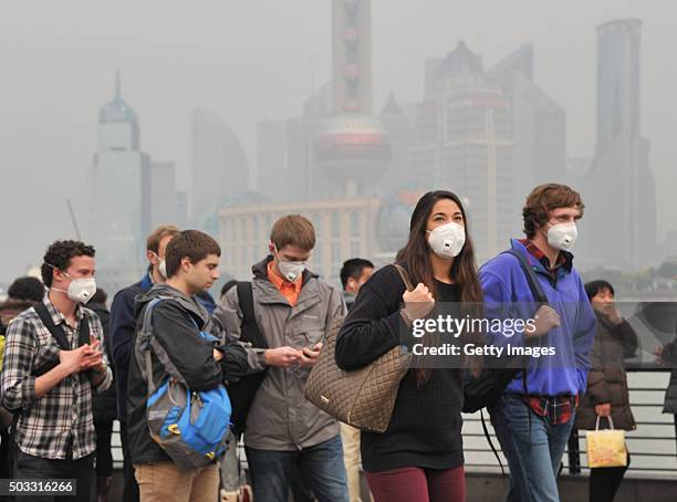 Tourists wearing breathing masks visit The Bund in the smog on January 3, 2015 in Shanghai, China. The air quality index in Shanghai reached 230 in...