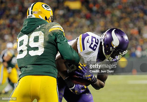 James Jones of the Green Bay Packers tackles Xavier Rhodes of the Minnesota Vikings after Rhodes intercepts a pass in the end zone during the fourth...