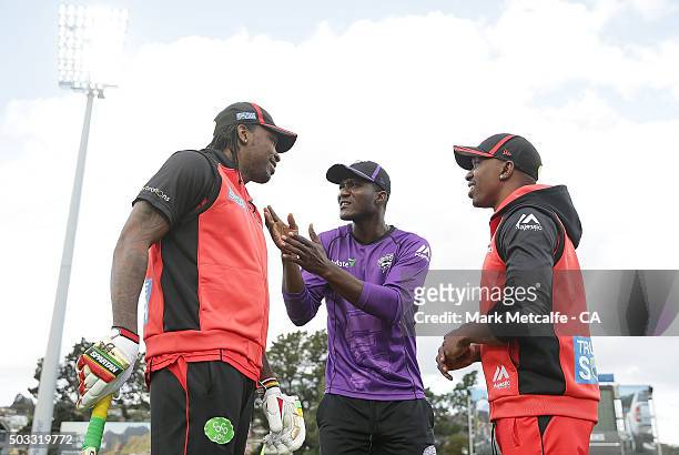 Chris Gayle and Dwayne Bravo of the Renegades and Darren Sammy of the Hurricanes talk on the field before the Big Bash League match between the...