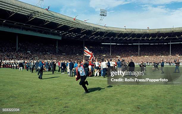 Young England supporter runs on to the pitch carrying a Union Jack flag after the FIFA World Cup Final between England and West Germany at Wembley...