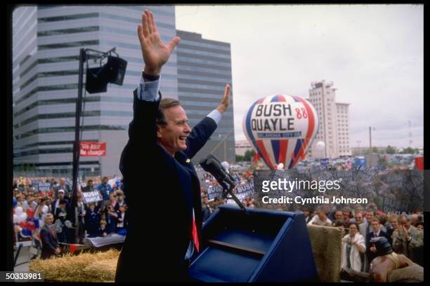 Republican presidential candidate VP George Bush raising arms triumphantly above supportive crowd at campaign rally graced by BUSH QUAYLE 88 hot air...