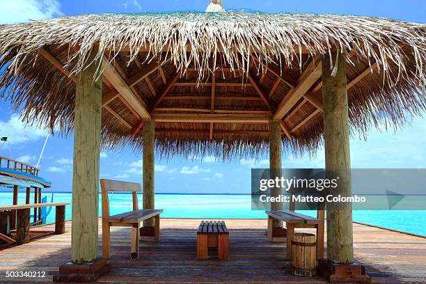 pier on tropical island with thatched roof and chairs, maldives - beach shelter ストックフォトと画像