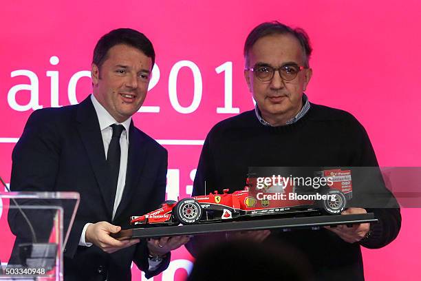 Sergio Marchionne, chief executive officer of Fiat Chrysler Automobiles NV, right, presents Matteo Renzi, Italy's prime minister, with a model...