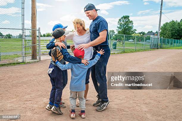 family of five in a group hug after baseball game. - baseball huddle stock pictures, royalty-free photos & images