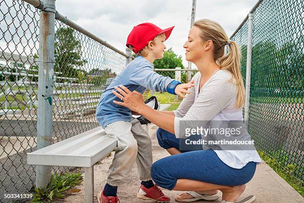 gracias mamá! madre e hijo abrazándose en banco de béisbol. - baseball mom fotografías e imágenes de stock
