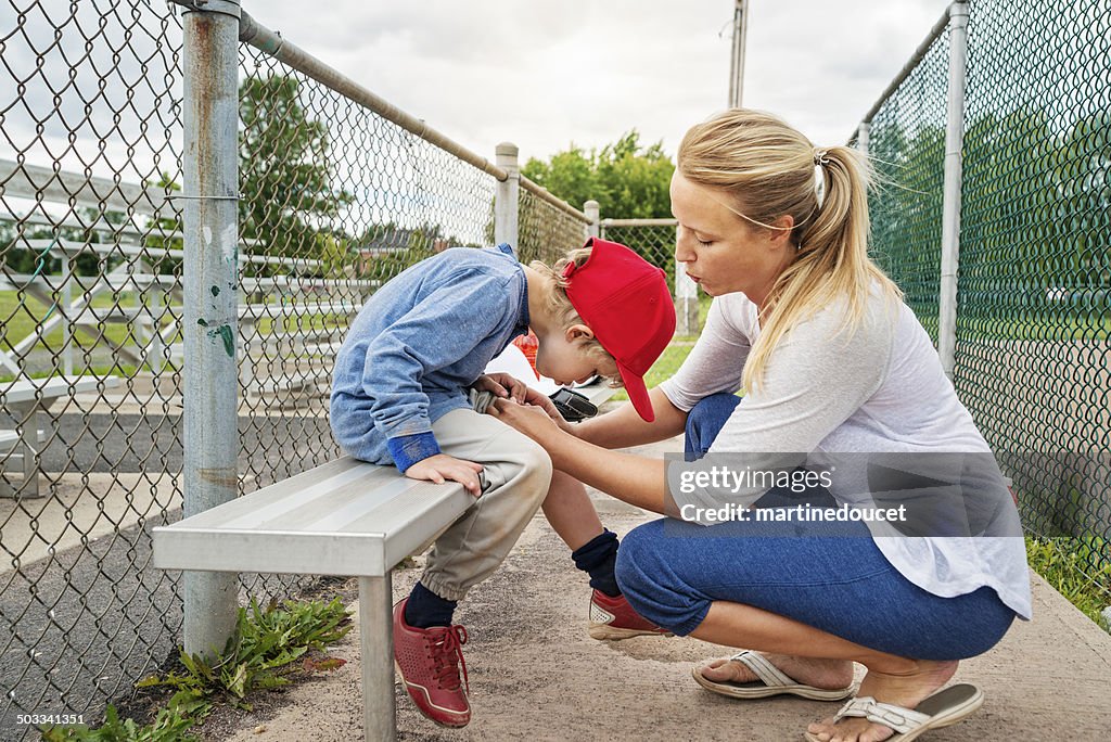 Mutter und Sohn Blasen auf ABGETRAGENES Knie auf baseball-Bank.