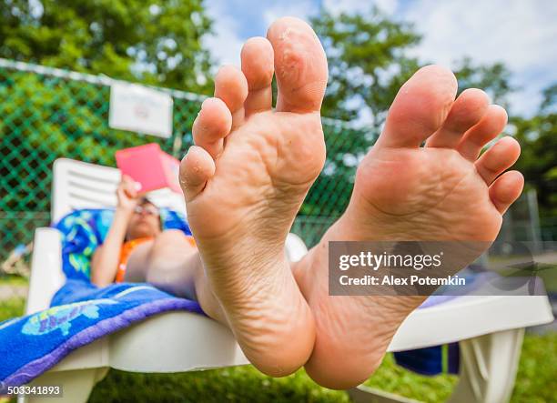 little girl reading book in the chaise lounge - girls soles stock pictures, royalty-free photos & images