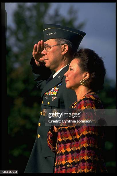 Outgoing Joint Chiefs Chmn. Gen. Colin Powell saluting during his Fort Meyer farewell fete, w. Wife Alma by his side.