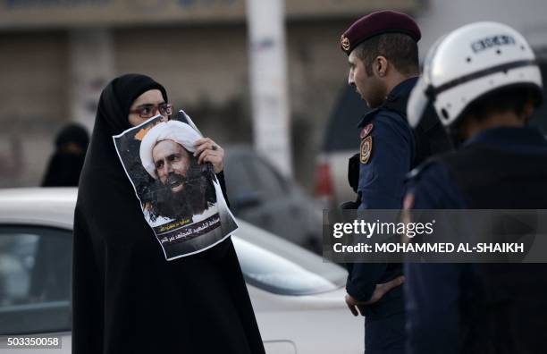 Bahraini woman holds a poster of prominent Shiite Muslim cleric Nimr al-Nimr during clashes with riot police following a protest against the...