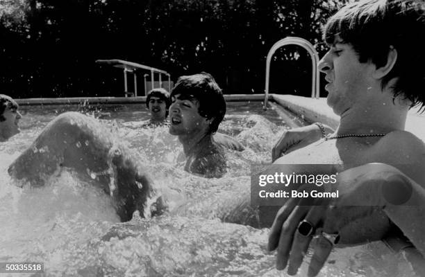 John Lennon, George Harrison, Paul McCartney & Ringo Starr, members of British rock group, The Beatles, frolicking in swimming pool.