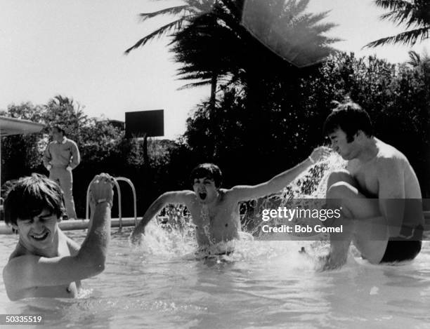 Ringo Starr, Paul McCartney & John Lennon, members of British rock group, The Beatles, frolicking in swimming pool.