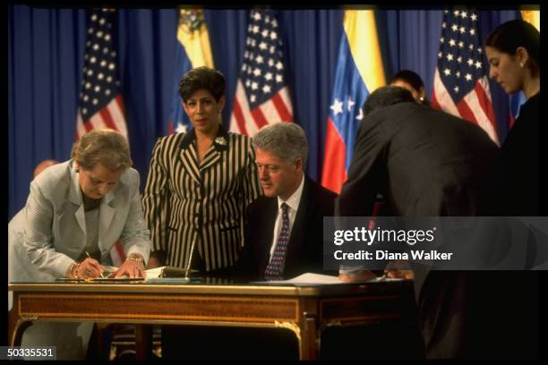 State Secy. Madeleine Albright penning agreement as Pres. Bill Clinton looks on during ceremony at Miraflores Palace.