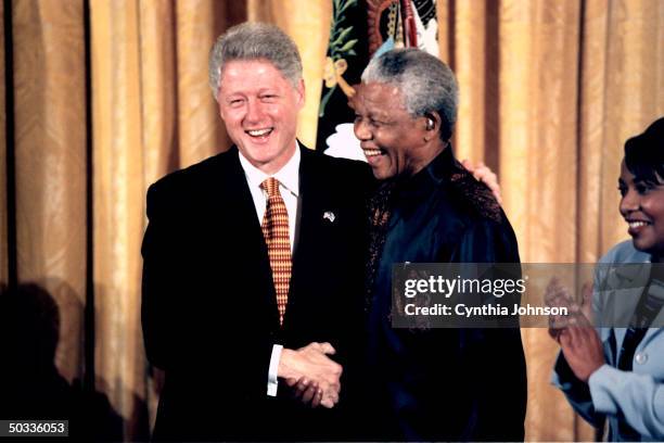 Pres. Bill Clinton shaking hands w. South African Pres. Nelson Mandela as Rev. Bernice King applauds during meeting w. African American religious...