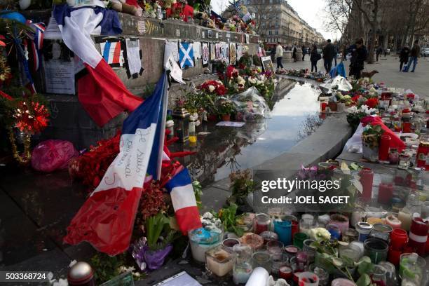 People stand next to the makeshift memorial in tribute to the victims of the Paris terror attacks, on January 4 at the Place de la Republique in...