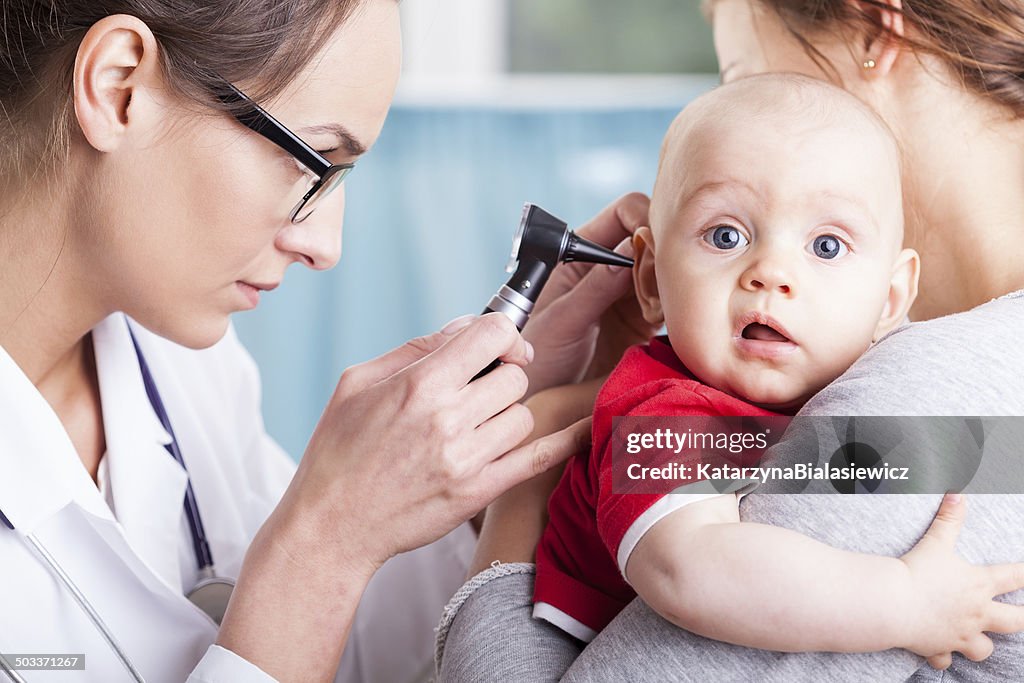 Doctor examining baby boy with otoscope