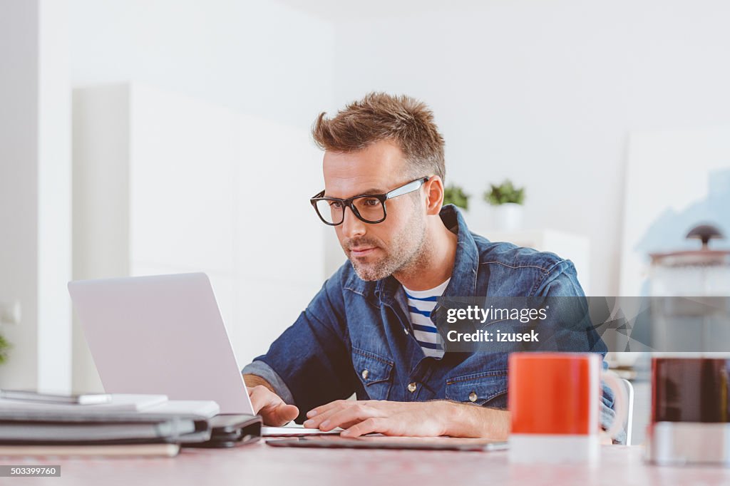 Uomo che lavora sul computer portatile a casa