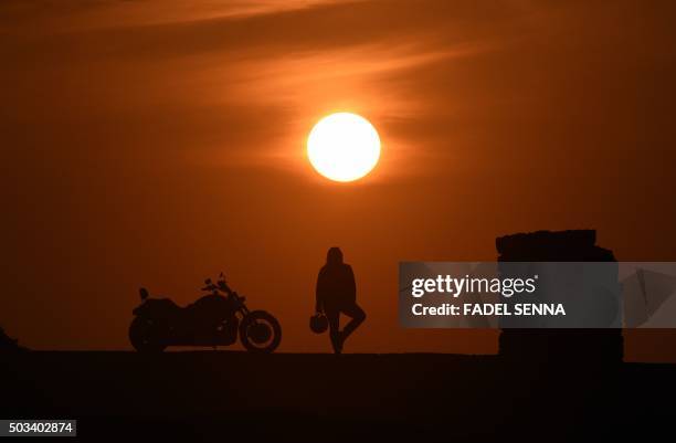 Mey Zniber, a Moroccan therapist poses at sunset next to her Harley Davidson motorbike on December 24, 2015 in the Moroccan capital Rabat. Mai has...