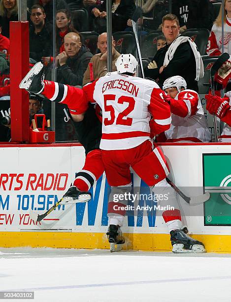 Jiri Tlusty of the New Jersey Devils is checked over the boards by Jonathan Ericsson of the Detroit Red Wings during the game at the Prudential...