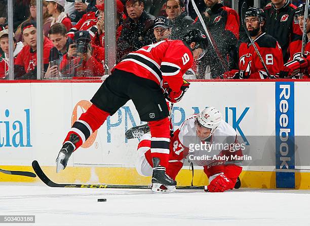 Alexey Marchenko of the Detroit Red Wings falls to the ice after being checked by Jiri Tlusty of the New Jersey Devils during the game at the...