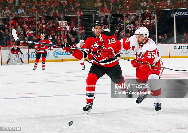 Travis Zajac of the New Jersey Devils and Niklas Kronwall of the Detroit Red Wings pursue a loose puck during the game at the Prudential Center on...