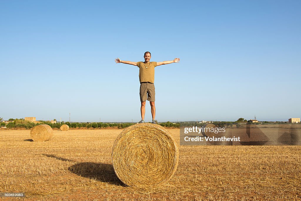 Young happy man on a bale of straw