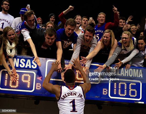 Wayne Selden Jr. #1 of the Kansas Jayhawks celebrates with fans as he leaves the court after the Jayhawks defeated the Oklahoma Sooners 109-106 in...