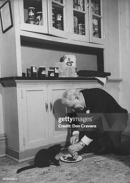 Gov. Luther Hodges, feeding his cat Carolina cat food.