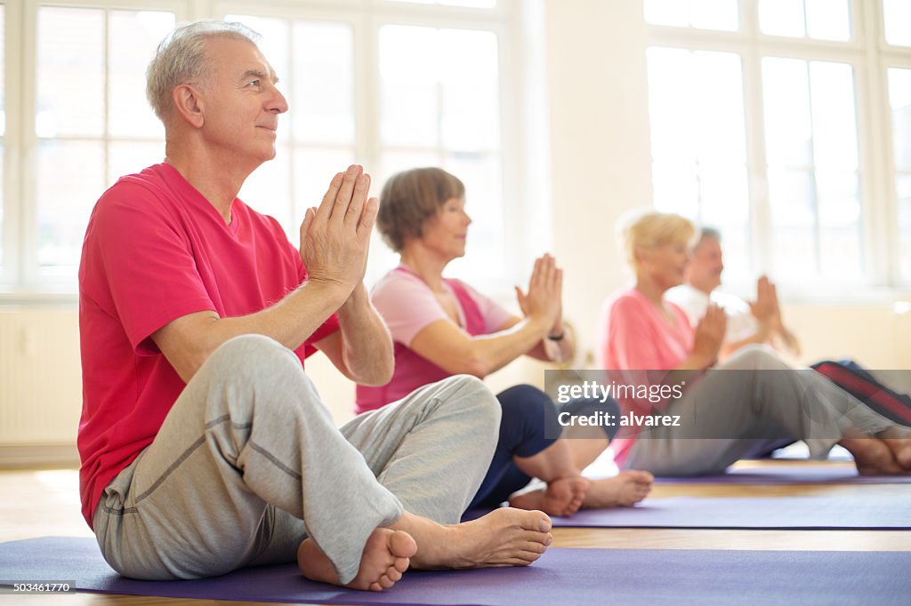 Senior people meditating in yoga class