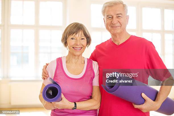 feliz pareja senior en gimnasio con una estera de yoga - intimate couple in gym fotografías e imágenes de stock