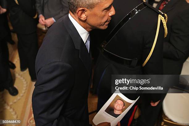 President Barack Obama carries a photograph of a victim of gun violence that was given to him after he delivered remarks about his efforts to...