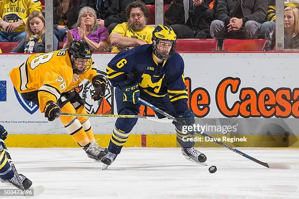 Sam Piazza of the Michigan Wolverines controls the puck in front of Brent Baltus of the Michigan Tech Huskies during the championship game of the...