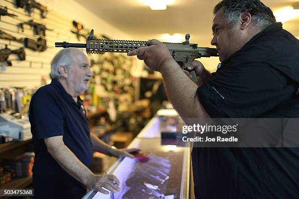 William Gordon, , helps Steve Wrona as he looks at weapons while visiting the K&W Gunworks store on the day that U.S. President Barack Obama in...