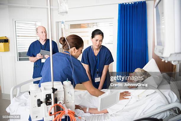 senior female patient in bed with concerned medical staff - hospital team with patient stock pictures, royalty-free photos & images