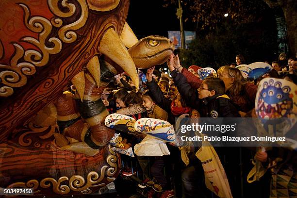 Children touch a balloon depicting a dragon during the 'Cabalgata de Reyes,' or the Three Kings parade on January 5, 2016 in Madrid, Spain. The...