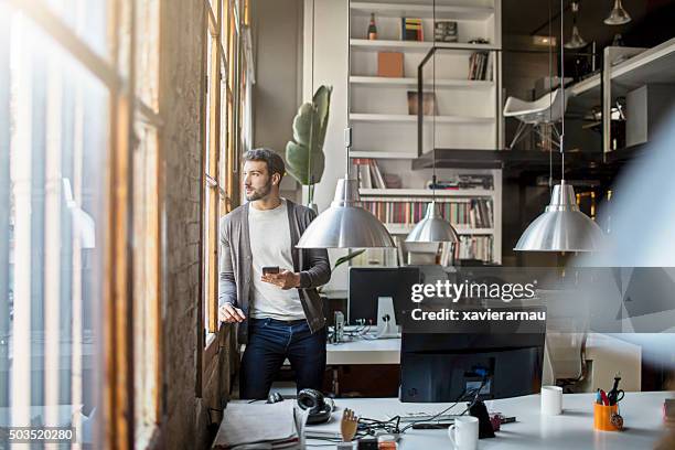 junge unternehmer auf der suche durch das fenster im büro - barcelona day stock-fotos und bilder