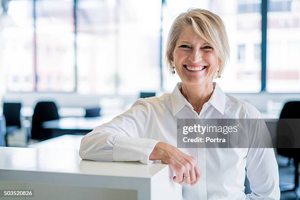 zufrieden geschäftsfrau gegen trennwand im büro - mature adult focus on foreground stock-fotos und bilder