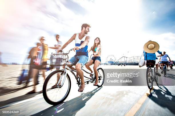 couple riding tandem bicycle in la - tandem bicycle stockfoto's en -beelden