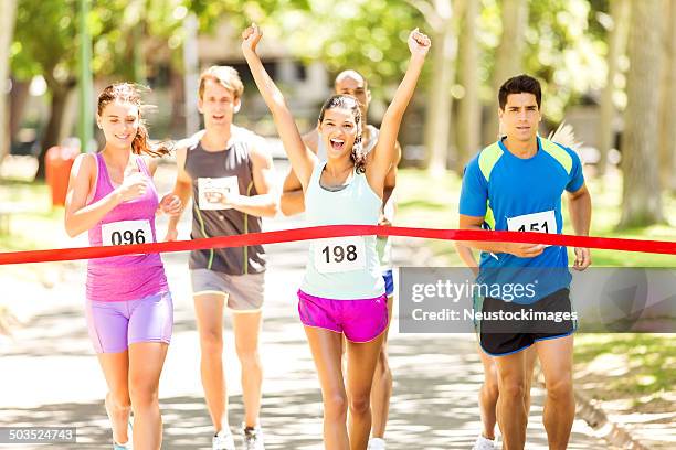 female marathon runner crossing finishing line - finish line ribbon stock pictures, royalty-free photos & images