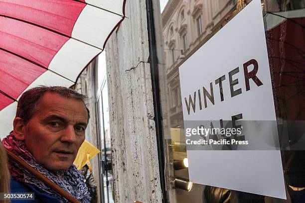 Customer looks at the window of a clothes shop offering discounts during the winter sales in downtown Rome, Italy. The first day of winter sales in...